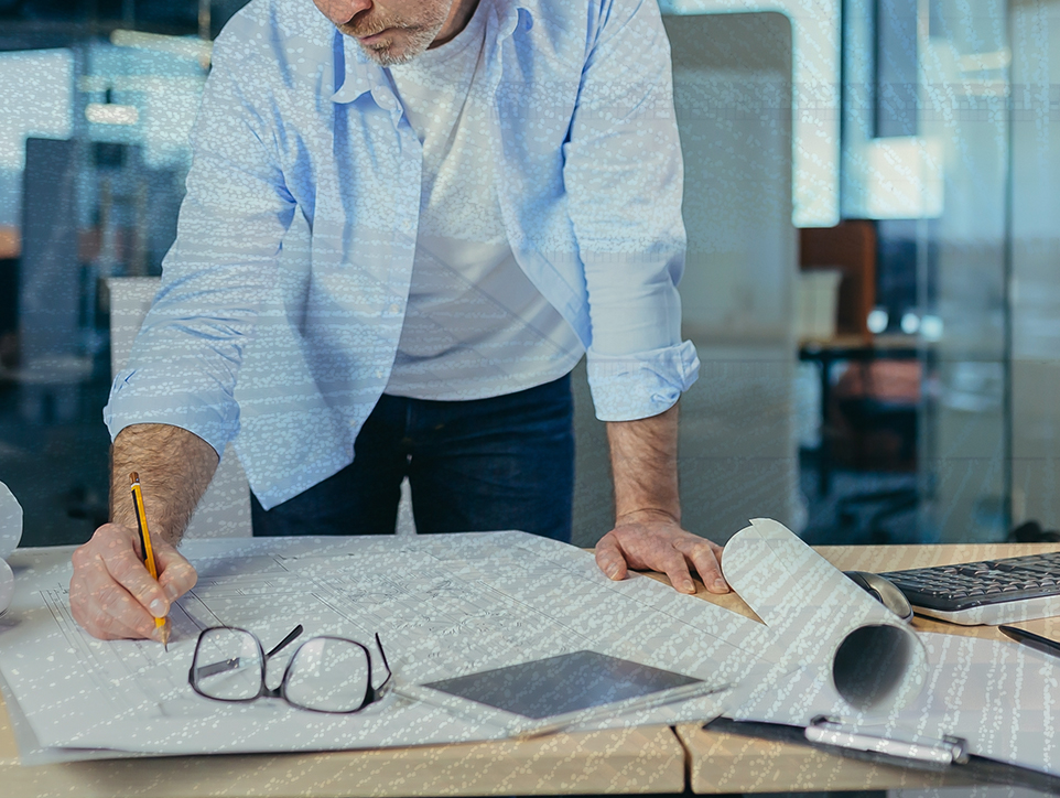 A man is working on a blueprint or architectural drawing.