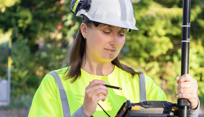 A person wearing a white hard hat and a yellow safety vest. 