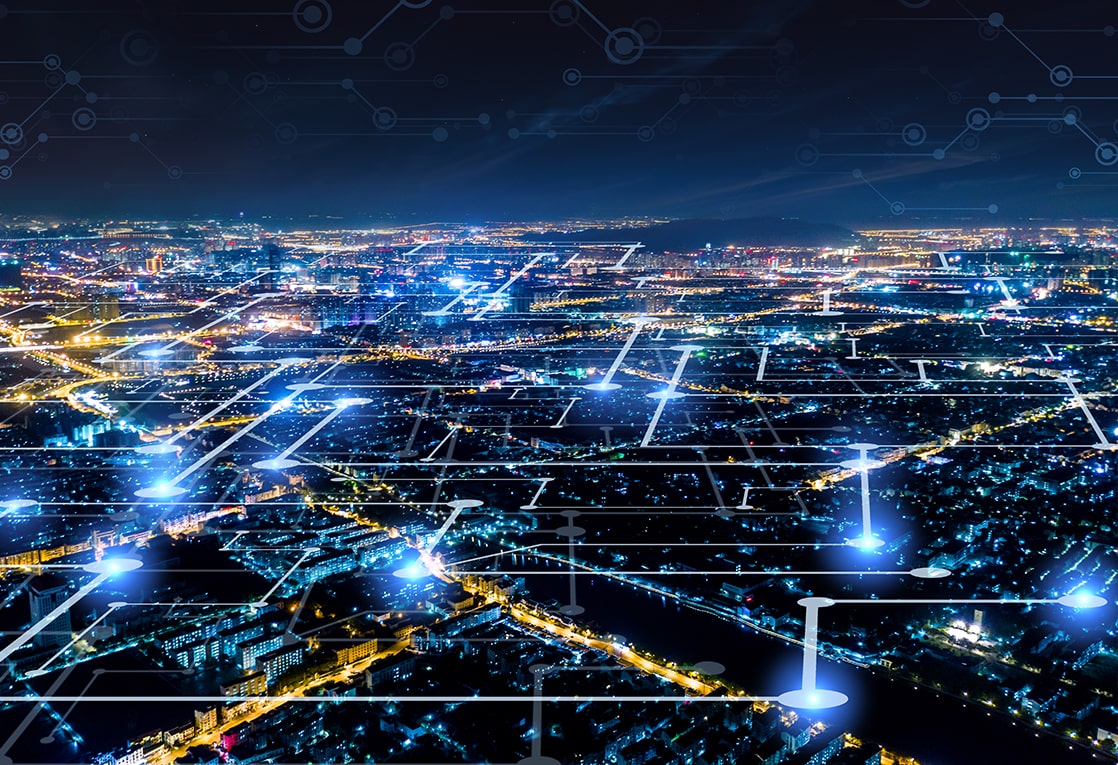  The city is seen from a high vantage point and the buildings and roads are lit up with different colors. The overlay consists of white lines and dots that form a network over the city. 