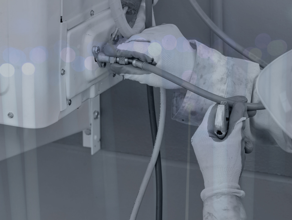 A black and white photo of a person’s hands wearing gloves and using a tool to work on an electrical panel.